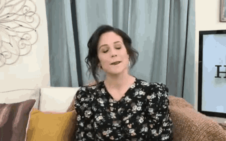 a woman is sitting on a couch with her eyes closed and her mouth open .