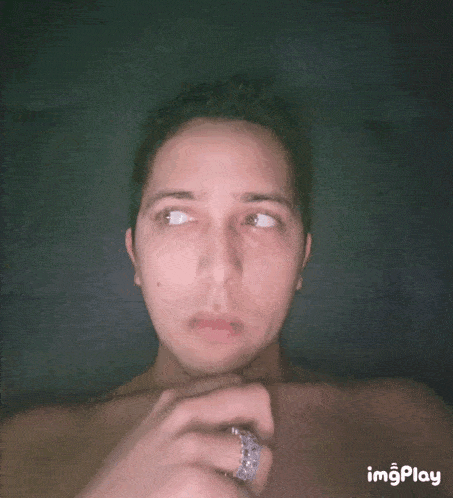 a shirtless man with a ring on his finger looks at the camera with imgplay displayed below his face