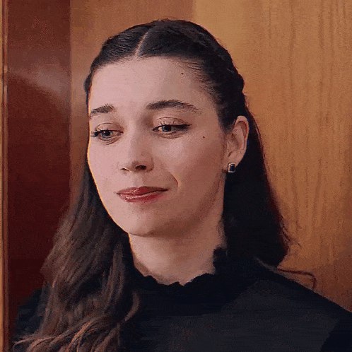 a close up of a woman 's face with a wooden wall in the background .