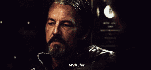 a man with a beard is talking to another man in a dark room .
