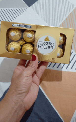 a person is holding a box of ferrero rocher