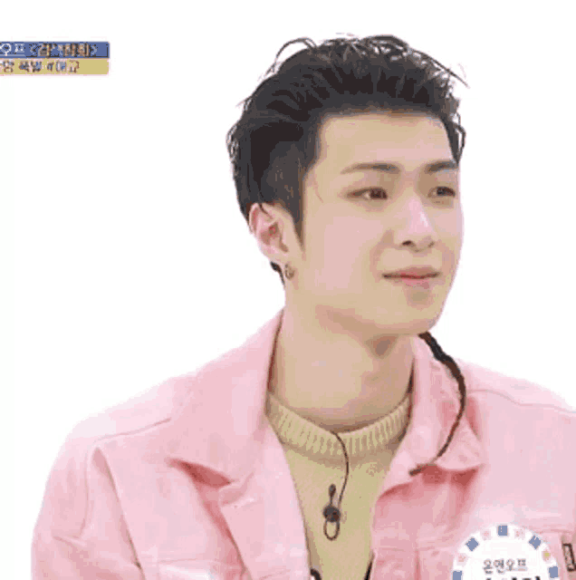 a young man wearing a pink jacket and a yellow sweater looks at the camera