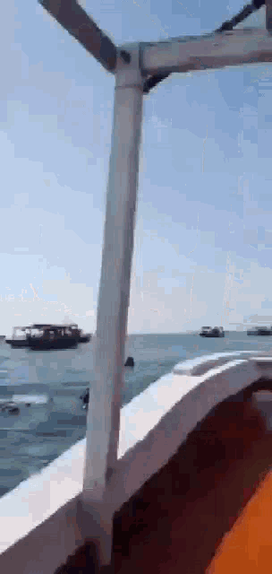 a boat is floating on top of a body of water with other boats in the background .