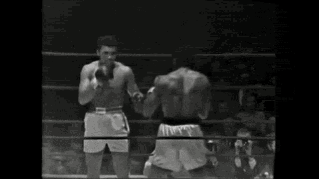 two boxers are fighting in a boxing ring in a black and white photo .