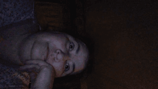 a woman is laying down with her hand on her face and looking at the camera .
