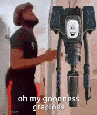 a man standing next to a robot that says oh my goodness gracious on it