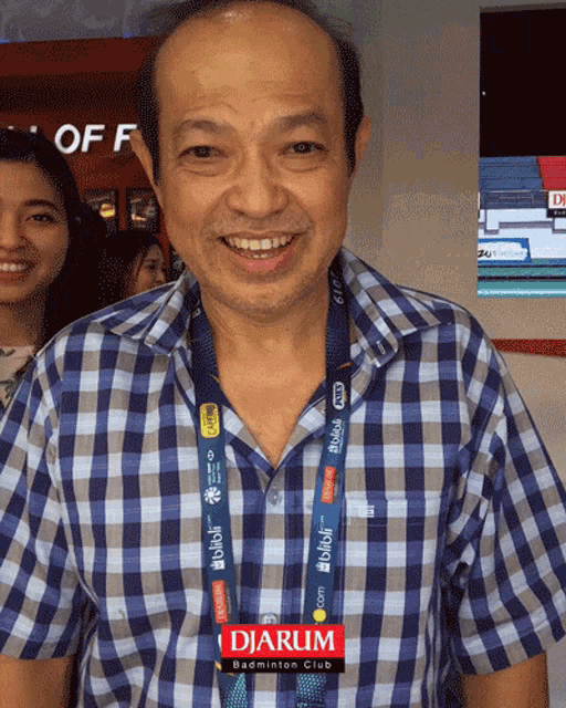 a man wearing a plaid shirt has a lanyard around his neck that says djarum badminton club