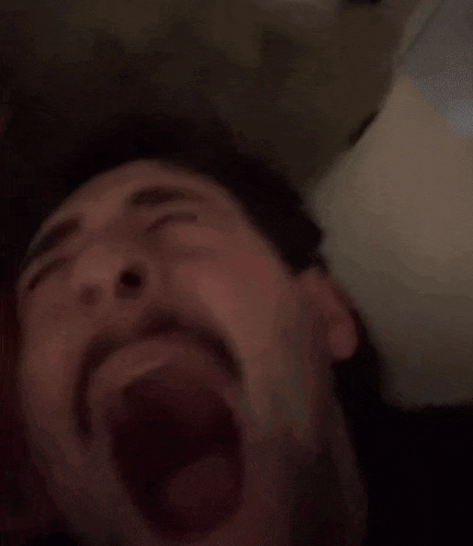 a man with a beard is making a funny face with his mouth open and his eyes closed .