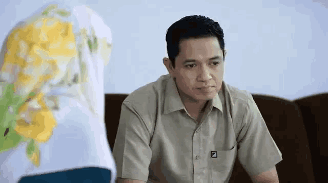 a man wearing a khaki shirt with the letter d on the front pocket