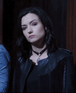 a woman wearing a choker and a leather jacket looks serious