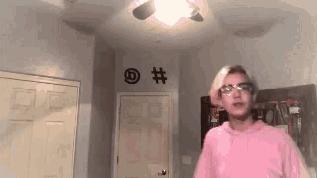a person in a pink hoodie is standing in a room with a ceiling fan