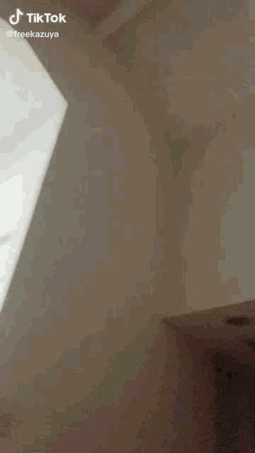a tiktok video of a person standing in a room with a white wall