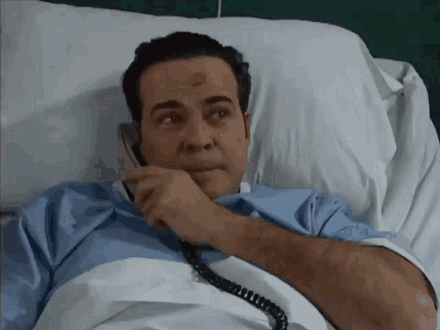 a man in a hospital bed talking on a cell phone