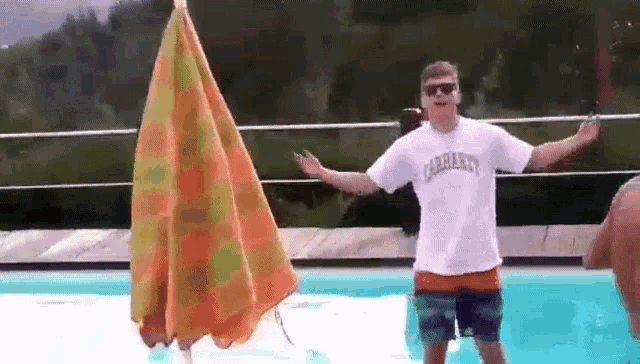 a man in a carhartt shirt is standing in a pool with his arms outstretched