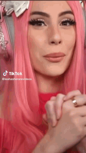 a woman with pink hair is wearing headphones and a ring .