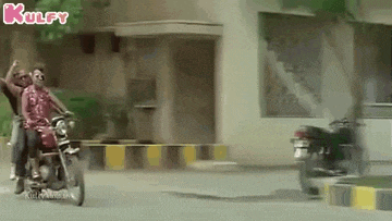 two men are riding a motorcycle down a street .