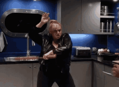 a woman is dancing in a kitchen with a toaster oven and a sink .