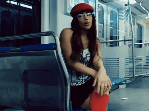 a woman wearing a red hat and glasses is sitting on a train