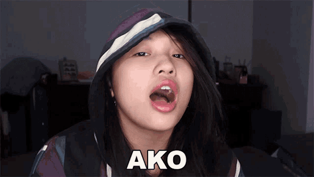 a girl wearing a hoodie is making a funny face and the word ako is above her mouth