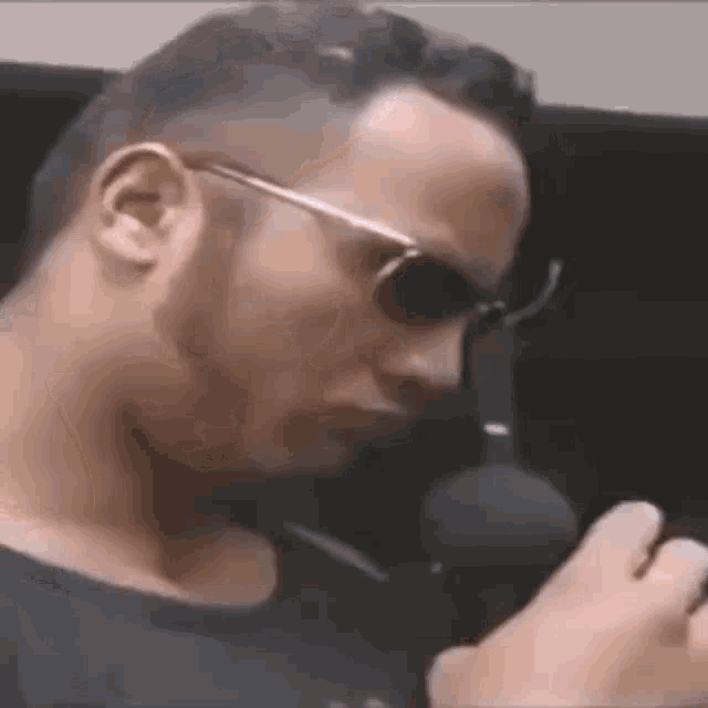 a man wearing sunglasses is holding a microphone in his hand .
