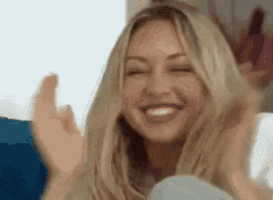 a woman with blonde hair is smiling and clapping her hands .