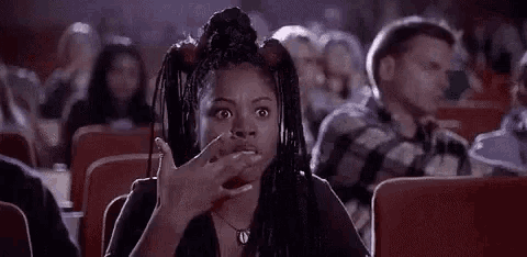 a woman with dreadlocks is sitting in a movie theater applauding .