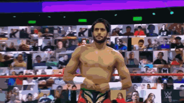 a shirtless wrestler stands in a wrestling ring with a crowd in the background