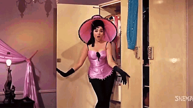 a woman in a pink hat and gloves is standing in front of a door that says shema