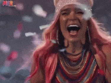 a woman with pink hair is laughing while confetti falls around her