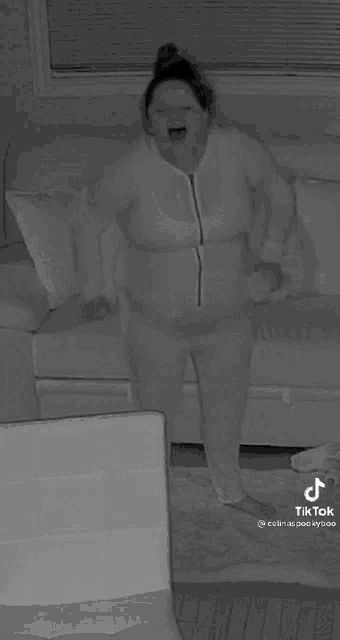 a woman in pajamas is standing in front of a couch with the words rip written on her chest .