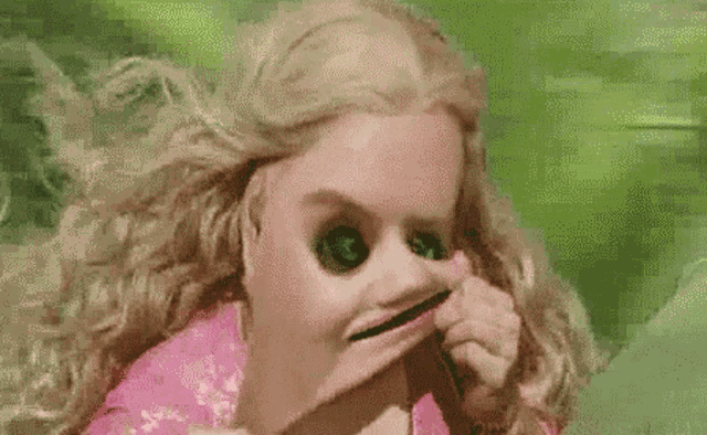 a woman in a pink dress is making a funny face while looking in a mirror .