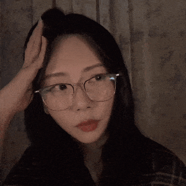 a woman wearing glasses is touching her hair