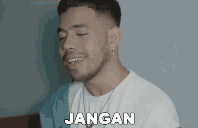 a man with a beard is wearing a white shirt and a blue jacket and says jangan .