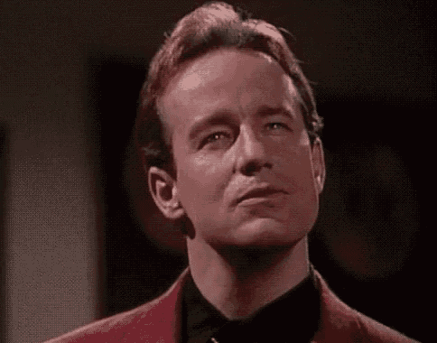 a man in a red jacket and black bow tie is making a funny face .