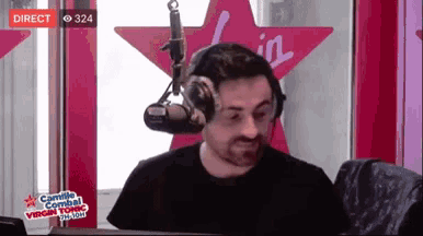 a man wearing headphones is sitting in front of a microphone in front of a pink star that says virgin tonic