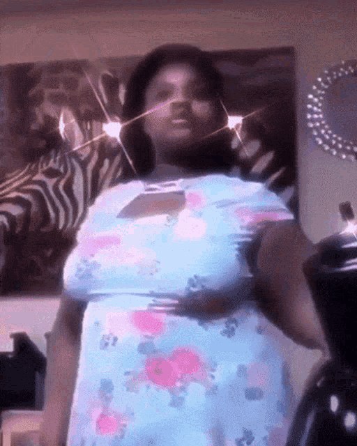 a woman in a blue floral dress is standing in front of a zebra print painting