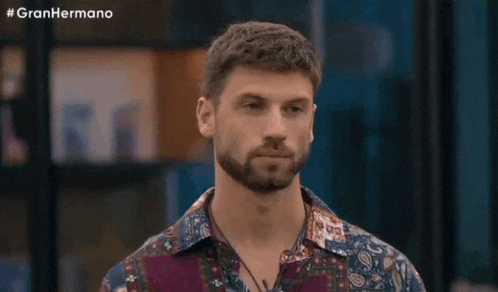 a man with a beard is wearing a colorful shirt and necklace .