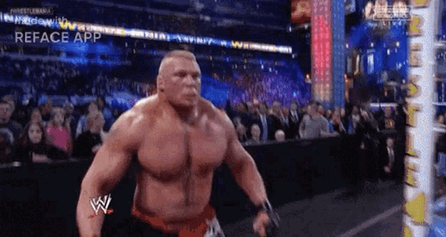 a wrestler is standing in front of a crowd while wearing a red belt with the letter w on it .