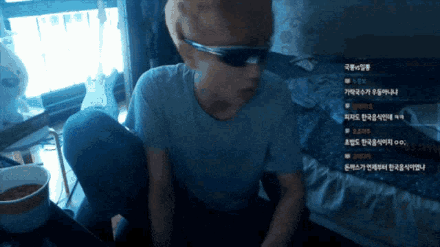 a man wearing sunglasses is sitting in front of a computer screen with korean writing on it