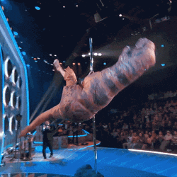 a t-rex is on a pole in front of a crowd of people