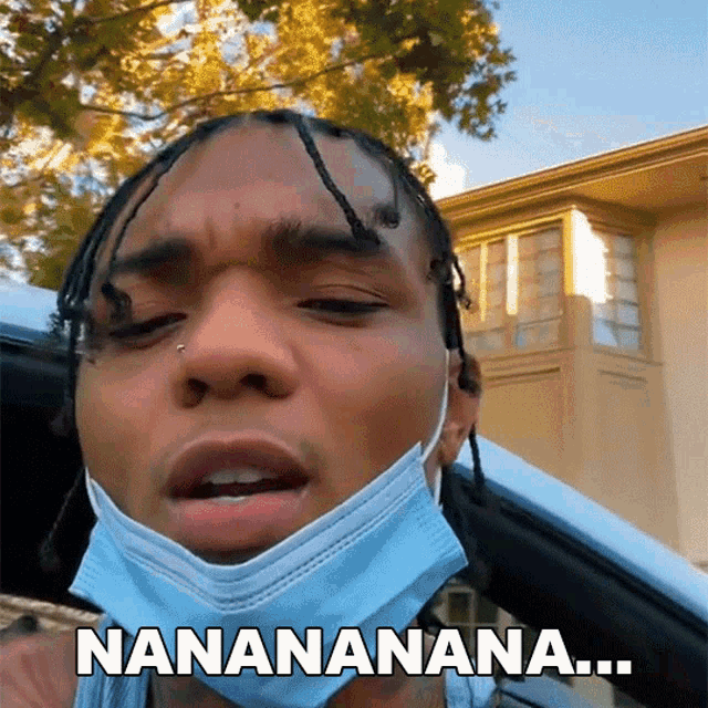 a man wearing a face mask says " nanananana " in front of a house