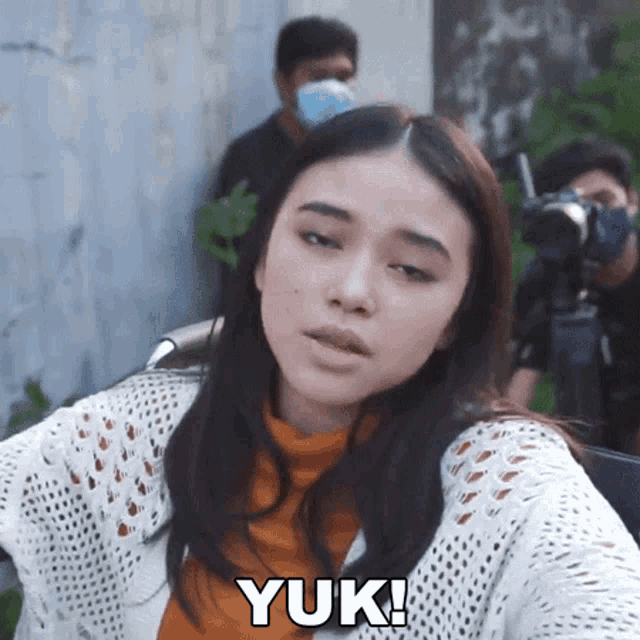 a woman is wearing a mask and the word yuk is on her shirt
