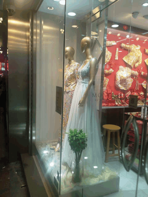 a mannequin in a wedding dress is in a store window that says mc on it