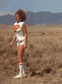 a woman wearing a superman shirt is standing in the desert with her fist in the air