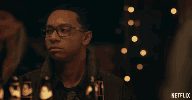a man with glasses sits at a table with bottles of beer and a netflix logo