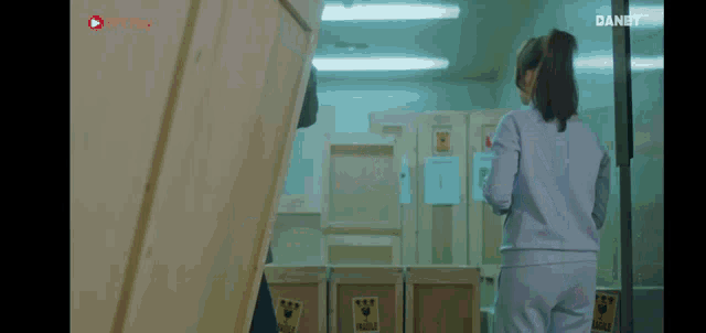 a woman in a ponytail is standing in a room with boxes and a sign that says dangt
