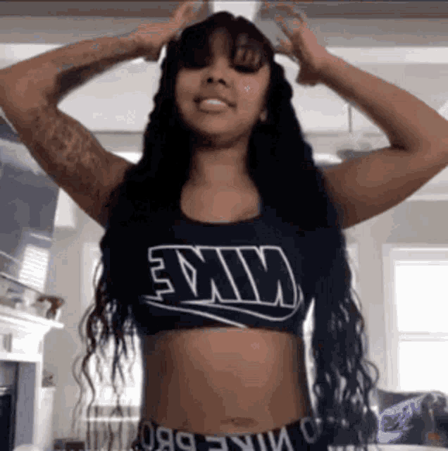 a woman wearing a nike crop top holds her hands to her head