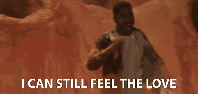 a man singing into a microphone with the words " i can still feel the love " below him