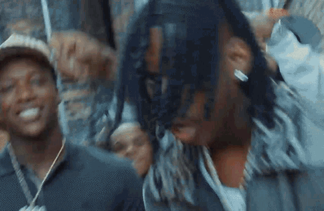a man with dreadlocks is standing in front of a crowd of people and smiling .