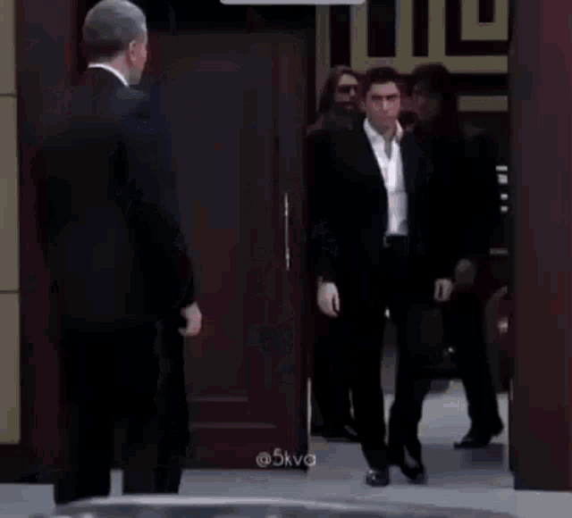a group of men in suits are walking in a room .